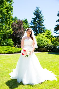 A bride poses for some portraits while wearing her wedding dress at a park outdoors just before here wedding ceremony.