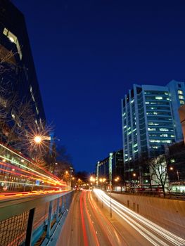 City banks and skyscrapers at night with traffic tail lights passing through 