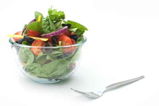 Fresh salad in a glass bowl over a white background
