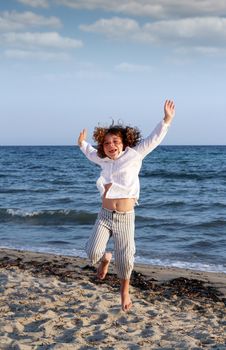 happy little girl jumping on beach summer scene