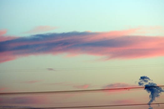 Clouds at sunset through powerline - with small cloud shaped like South America in the lower right corner