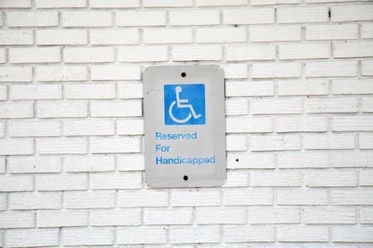 Handicapped parking sign on white brick background