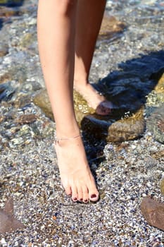 Woman wet feet on stones. Close-up. Background.