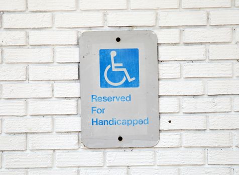 Handicapped parking sign on white brick background
