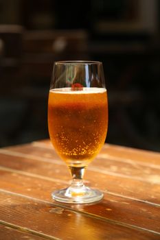 Goblet of beer are located on wooden table in dark