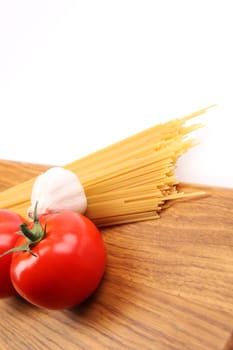 Spaghetti with ingredients on a wooden cutting board closeup