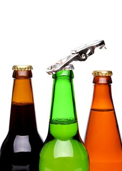 Threee bottles of beer and a opener on the white background