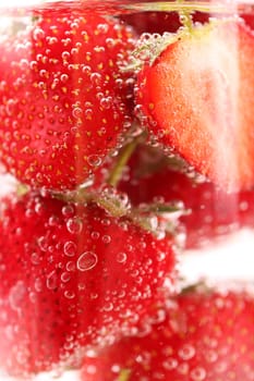 Strawberries with bubbles in water close-up as background