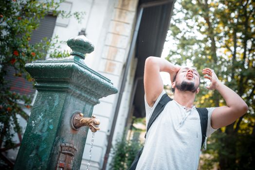 stylish man refreshing at the fountain at the park