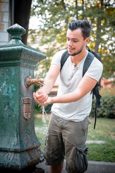 stylish man refreshing at the fountain at the park