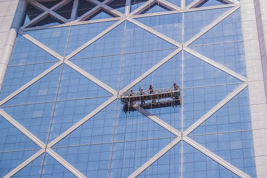 Santiago, February 2011. Professional workers clean the windows of an skyscraper from outside with a platform.