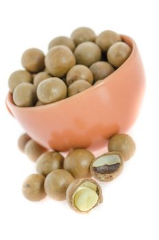 Shelled and unshelled macadamia nuts  in a cup on white