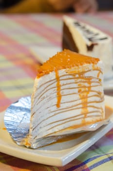 close up orange crepe cake on white plate