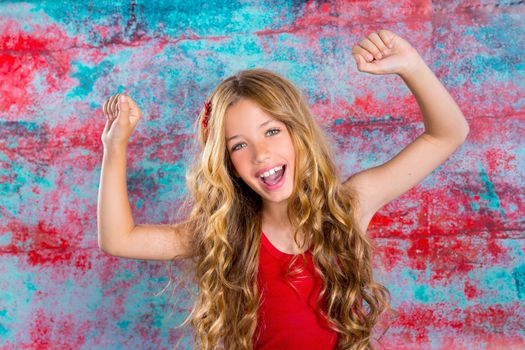 Blond happy children girl in red happy with arms up in grunge background