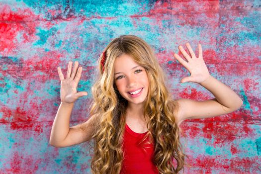 Blond happy children girl in red happy with arms up in grunge background