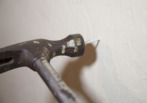 Hammer striking nail on wall with hammer shadow