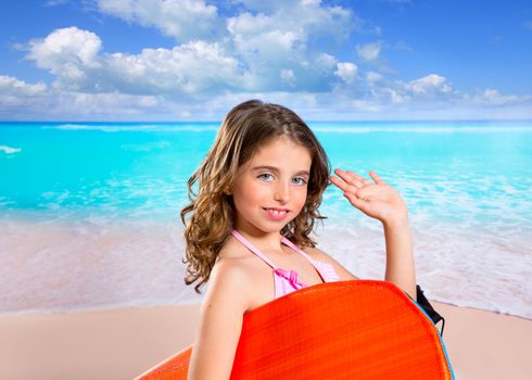 Children fashion surfer girl in tropical turquoise beach vacation with greeting hand