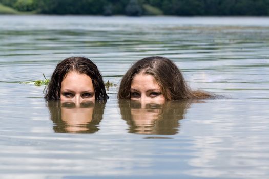 Two girls, mermaids swim in the lake