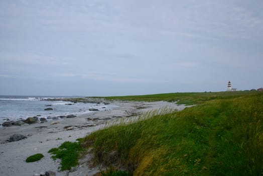 A path along the beach with a lighthouse in the distance