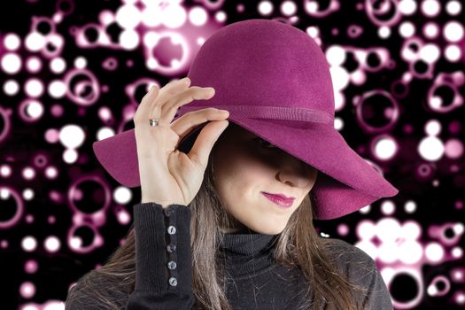 Portrait of beautiful young girl with a garnet hat on her head, in front of spotlights background