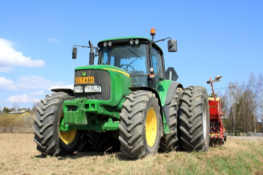 SALO, FINLAND- MAY 11, 2013: John Deere 6620 agricultural tractor and cultivator on field in Salo, Finland on May 11. On June 28, John Deere announces New Mobile Version to parts and services for a convenient access even in field.