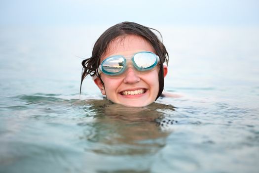 Closeup portrait of smiling teenage girl with goggles in water