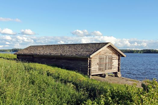 Old boat house by lake Rautavesi by St Olaf Church in Tyrvaa, Finland on a clear evening at summer.