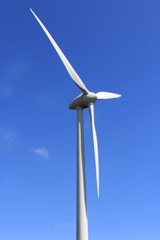 Wind turbine against blue sky, showing rotation of the blades.