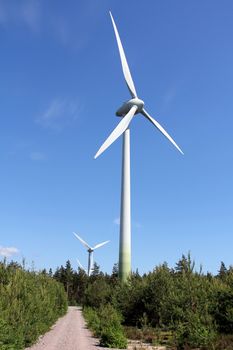 Wind turbines in forest against blue sky at summer. Photographed near Hanko, Finland in June 2013.