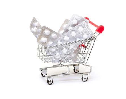 White pills packs in shopping cart, on white background