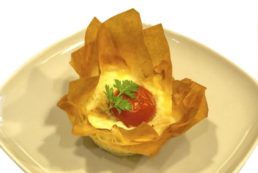 Small homemade pie with cheese and cherry tomato in a basket of pastry