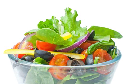Fresh salad in a glass bowl over a white background