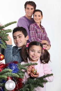 happy parents with children decorating Christmas tree
