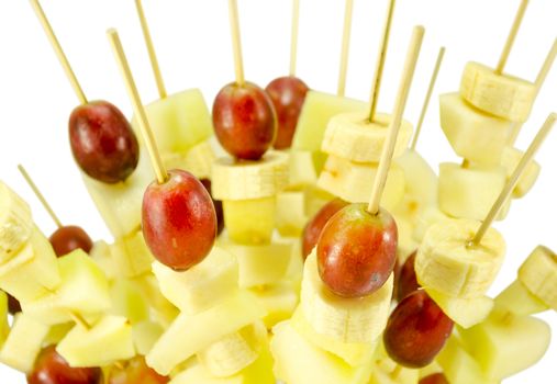 closeup of fruit grape and banana piece scewers on wooden broachs inserted. healthy diet food decoration.