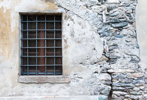 Window closed grate against the background of an old wall