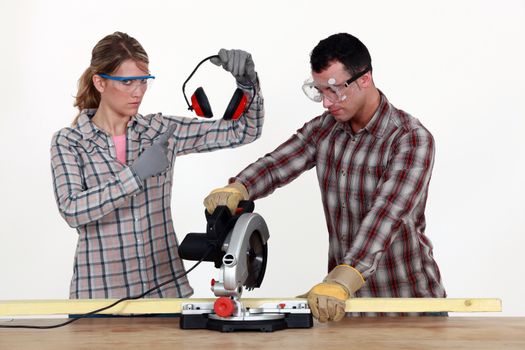 Woman making sure man uses hearing protection