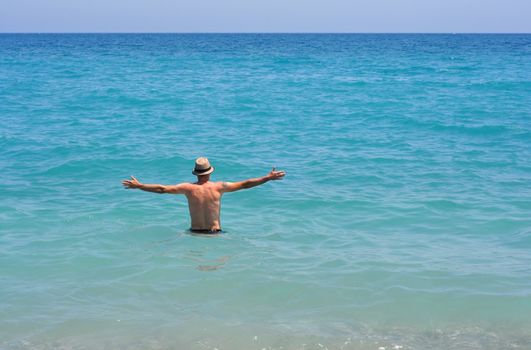 young man with hat into the mediterranean sea water