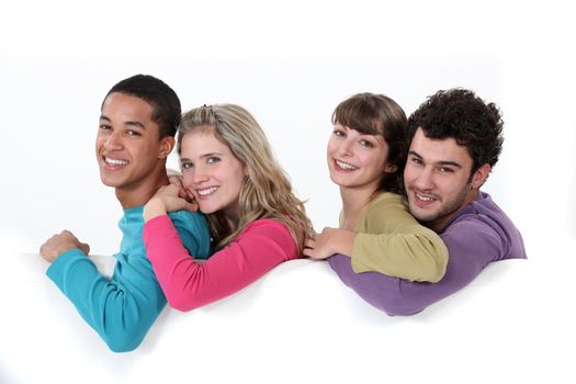 Two young couple stood by blank poster