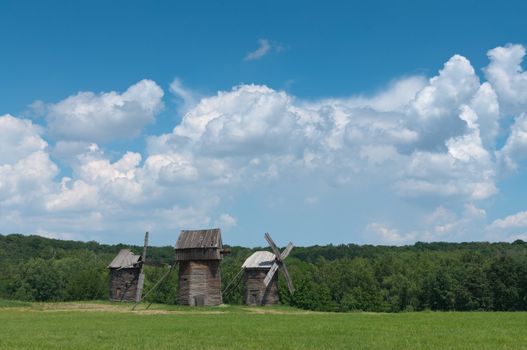 Three old wooden windmills on the field.