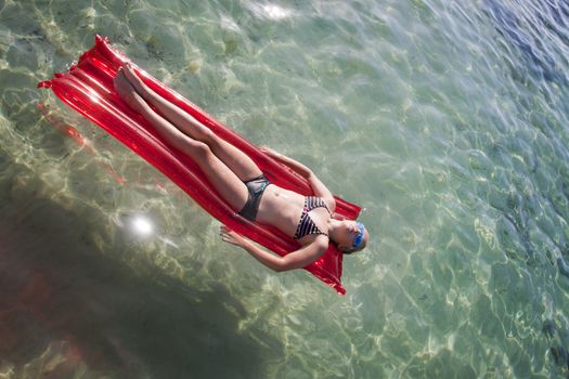 Child on lilo floating on crystal clear water