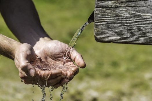 Thirsty Hands taking water from a well in the Alps