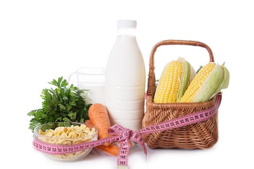 Milk, cereals and some vegetables tied up by measure tape on white