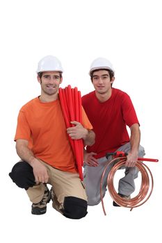 Kneeling tradesmen holding building materials and tools