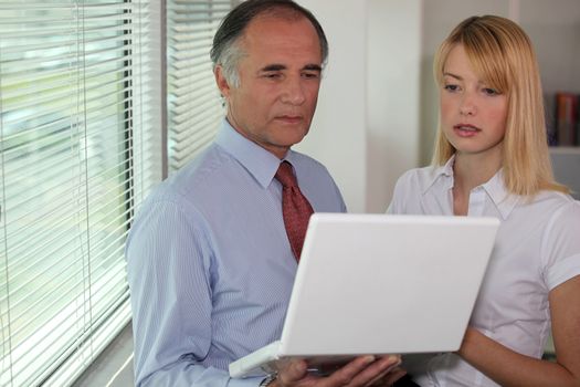 Businessman looking at a laptop with his assistant