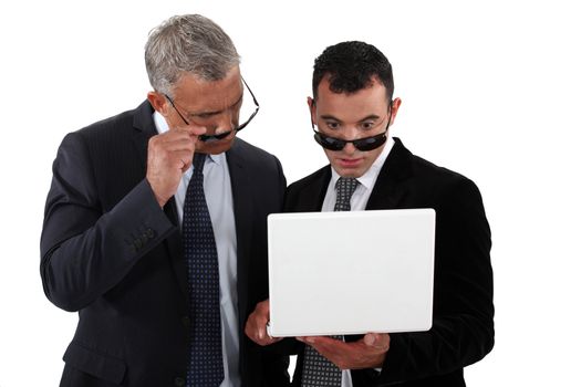 businessmen wearing sunglasses looking at a laptop