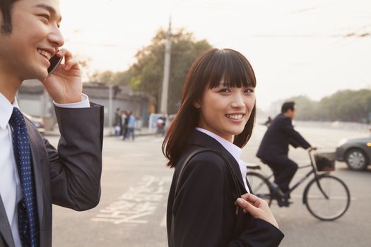 Two young business people outside on the street using phone in Beijing