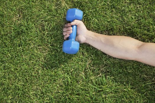 Close Up on Hand Holding Blue Dumbbell in Grass