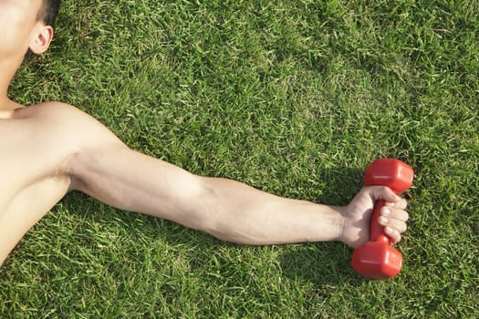 Close Up on Arm and Shoulder Holding Dumbbell in Grass
