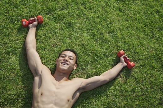 Shirtless Man Lying in Grass with Dumbbells in Beijing