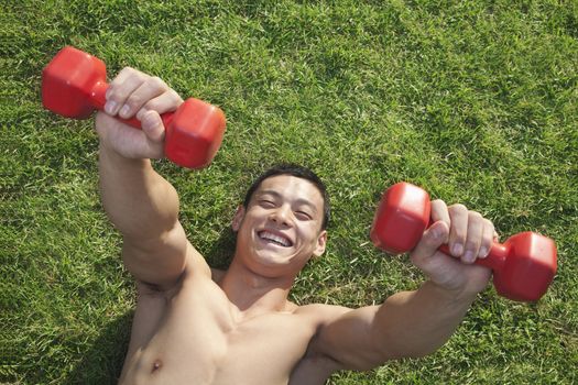 Shirtless Man Exercising with Dumbbells in Grass